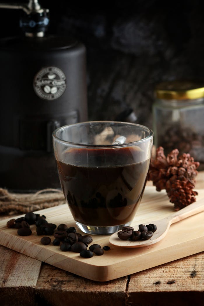 Close-up of a steaming glass of black coffee surrounded by beans, evoking rich aromas.